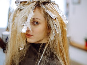 Eine junge Frau ist beim Frisör und hat Alufolie auf dem Kopf | © GettyImages/Tatsiana Volkava