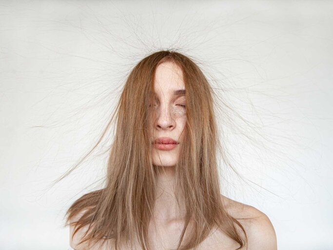 Junge Frau mit geschlossenen Augen und fliegenden, dünnen Haaren | © Getty Images/Iuliia Isaieva