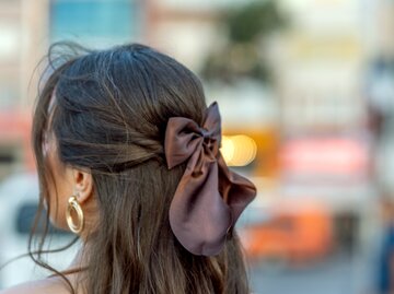 Eine junge Frau mit wunderschönem Haar und einer Schleife darin. | © Getty Images/turk_stock_photographer