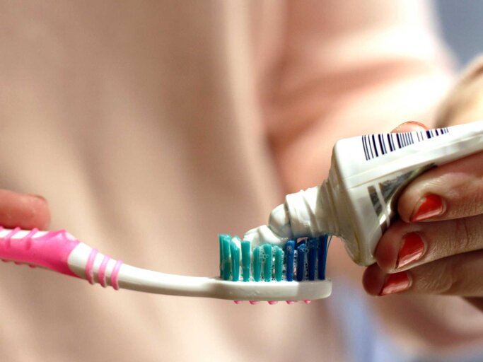 Frau drückt Zahnpasta auf Zahnbürste aus | © Getty Images/Isabel Pavia