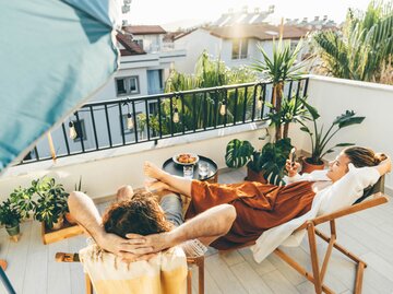 Paar relaxt auf ihrem schön gestalteten Balkon | © Getty Images/Maria Korneeva