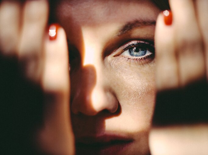 Frau hält sich Hände seitlich an den Kopf und schaut direkt in die Kamera | © Getty Images/Guido Mieth