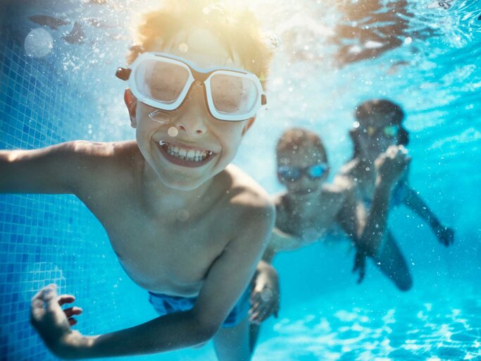Kinder spielen unter Wasser im Pool | © Getty Images/Imgorthand