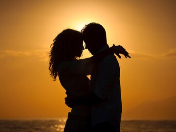 Paar umarmt sich am Strand bei Sonnenuntergang | © Getty Images/WillSelarep