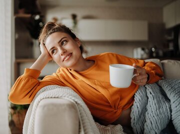 Person mit Tasse auf Couch | © Getty Images/Halfpoint Images