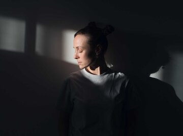 Junge Frau im verdunkelten Raum | © Getty Images/Aleksandr Zubkov