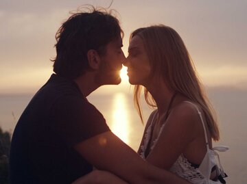 Junges Paar küsst sich bei Sonnenuntergang | © Getty Images/janiecbros