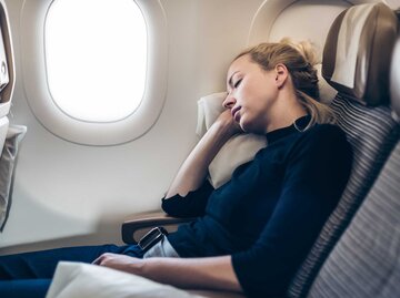 Müde blonde Frau sitzt im Flugzeug und schläft. | © Adobe Stock/kasto