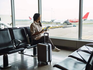 Person sitzt am Flughafen | © Getty Images/MStudioImages