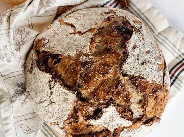 Ein frisch gebackenes Brot auf einem Küchentuch | © Unsplash/Jennifer Burk