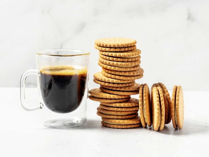 Eine Tasse Kaffee und ein Stapel Kekse auf einem Tisch | © Getty Images/Claudia Totir