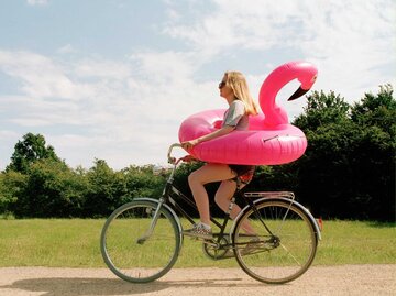 Frau fährt Fahrrad mit einem riesigen Flamingo-Schwimmreif | © Getty Images/Muriel de Seze