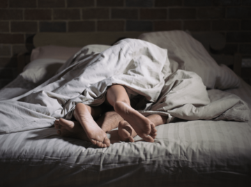 Füße von Mann und Frau unter der Bettdecke | © Getty Images/Supachok Pichetkul/EyeEm