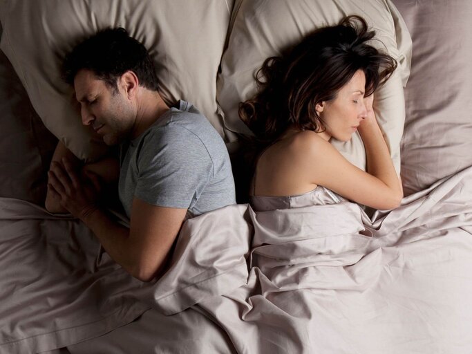 Mann und Frau liegen Rücken an Rücken im Bett | © Getty Images/Vincent Besnault