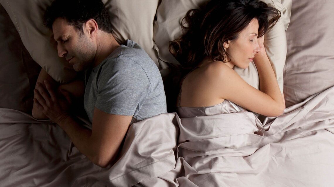 Mann und Frau liegen Rücken an Rücken im Bett | © Getty Images/Vincent Besnault