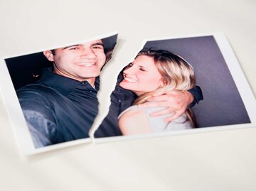 Ein Foto von einem glücklichen Paar liegt in der Mitte durchgerissen auf dem Tisch.  | © Getty Images / Jamie Grill