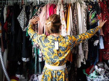 Blonde Frau Rückenansicht mit Etikett vor ihrem vollen Kleiderschrank | © Getty Images/Westend61