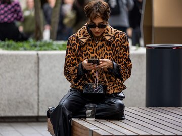 Person sitzt mit Handy in der Hand | © Getty Images/Christian Vierig