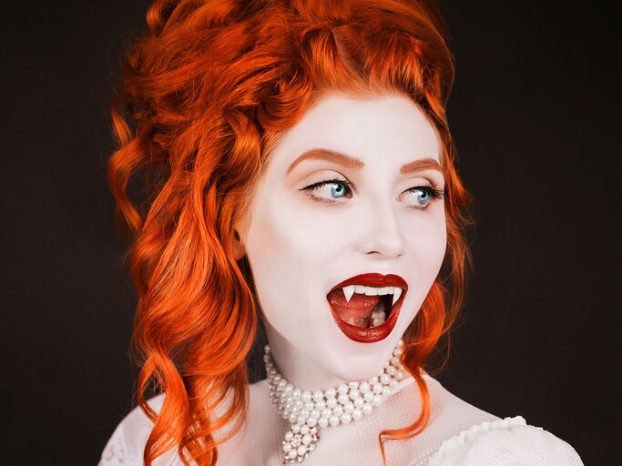 Frau mit roten Haaren geschminkt als Vampir an Halloween | © iStock.com / iiievgeniy