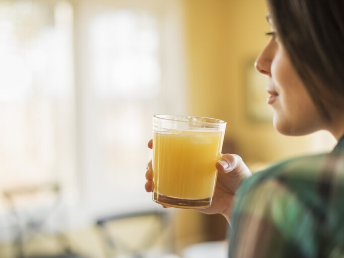 Frau hält Glas Orangensaft in der Hand | © Getty Images/Mint Images