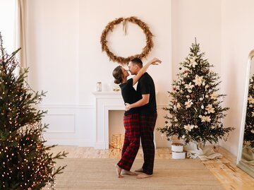 Paar steht verliebt in einer weihnachtlich dekorierten Wohnung | © Getty Images/Elizaveta Starkova
