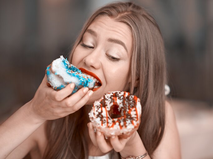 Junge Frau isst zwei Donuts | © Getty Images/	stock_colors