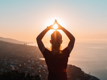 Frau macht Yoga beim Sonnenaufgang | © Getty Images/rbkomar