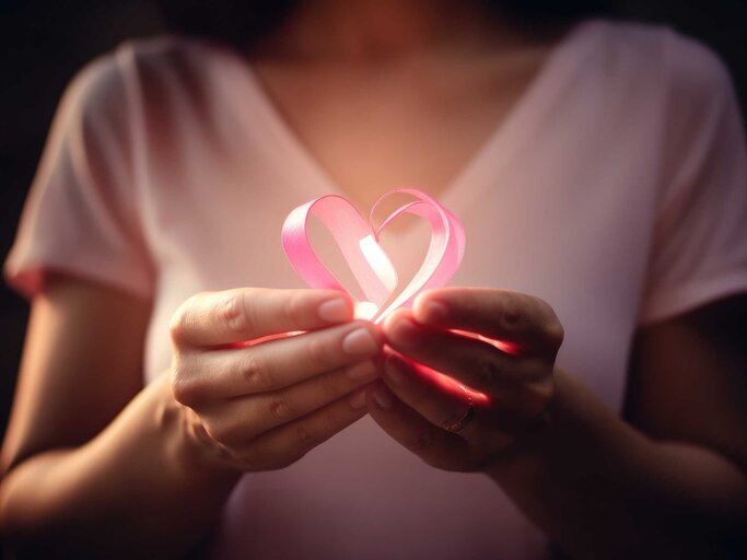 Frau hält pinkes Herz in der Hand | © Adobe Stock/Mustafa