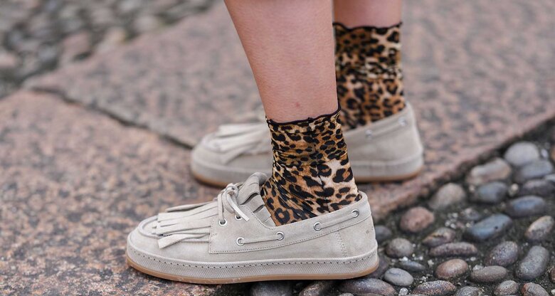 Frau trägt beige Bootsschuhe mit Leoparden-Socken auf der Straße. | © Getty Images/Edward Berthelot