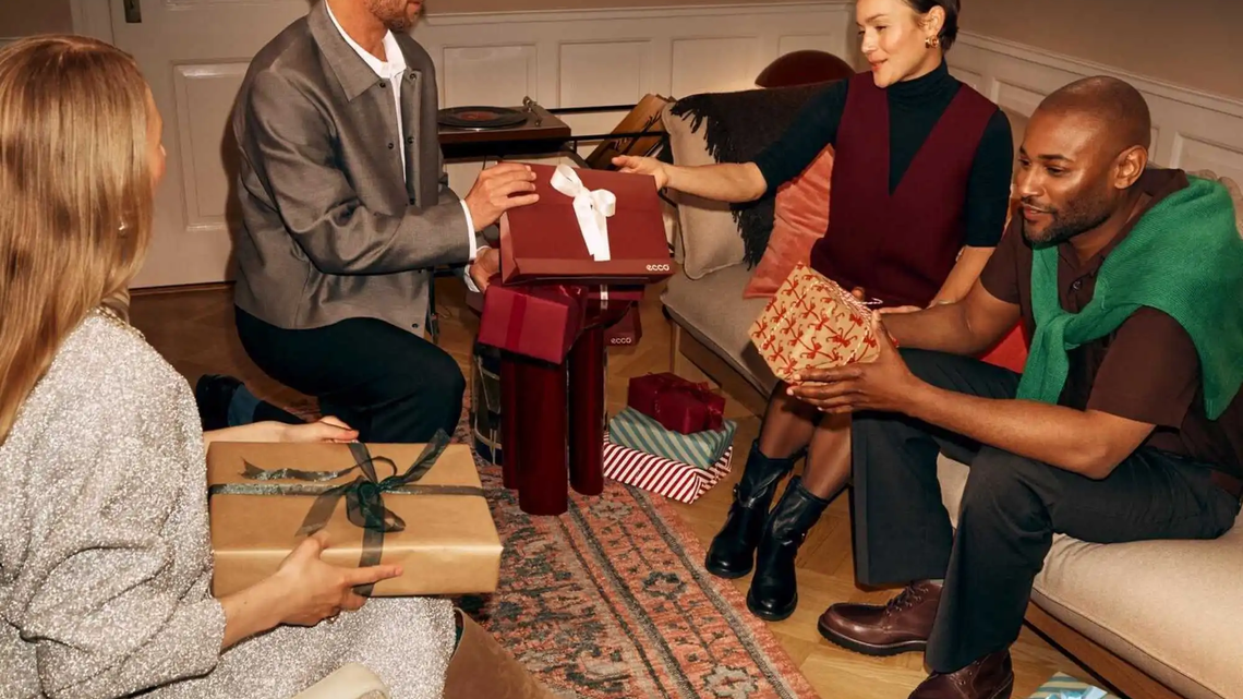 Festlich gekleidete Menschen tauschen Geschenke aus | © ECCO