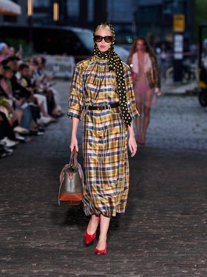 Model in kariertem Kleid und gepunkteten Kopftuch auf dem Laufsteg von Caro Editions | © Copenhagen Fashion Week/James Cochrane