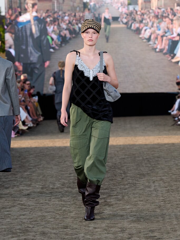 Model in schwarzem Spitzentop und grünen Cargohosen auf dem Laufsteg von Baum & Pferdgarten | © Copenhagen Fashion Week/James Cochrane