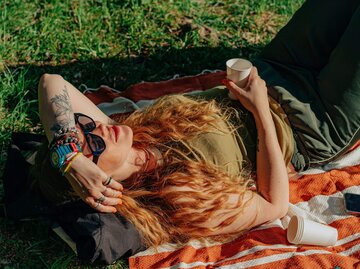 Person liegt auf Wiese in der Sonne | © Getty Images/Olena Malik