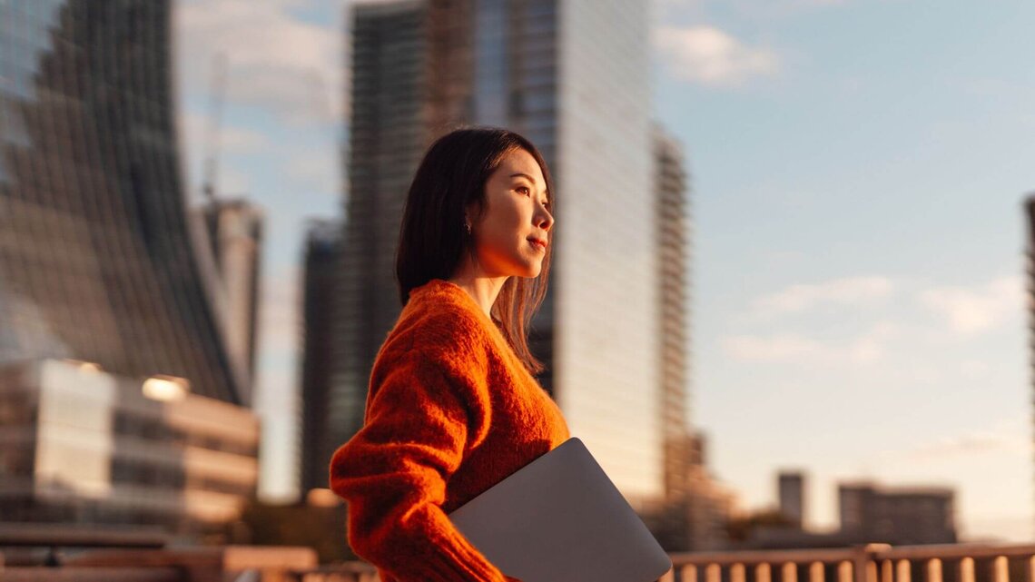 Person mit Laptop vor Skyline | © Getty Images/Oscar Wong