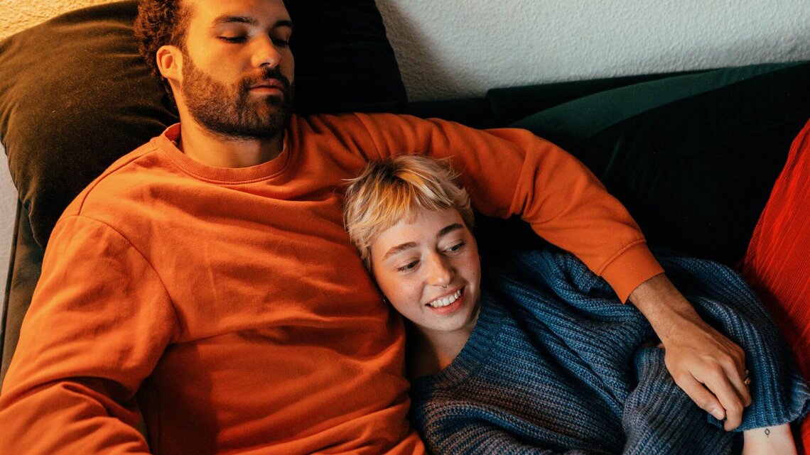 Paar liegt zusammen auf Sofa | © Getty Images/Alina Rudya/Bell Collective