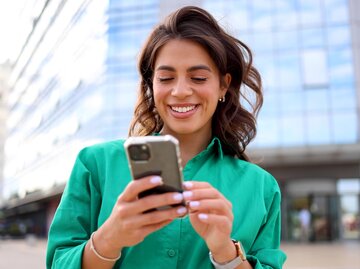  Junge Frau nutzt einen Moment in der Stadt, um auf ihrem Smartphone zu surfen | © Adobestock/PeopleVideos