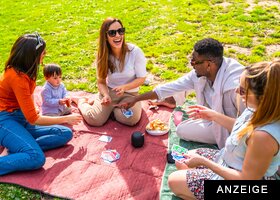 Familie spielt Karten auf Picknickwiese im Sommer