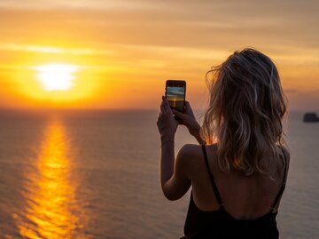 Frau fotografiert mit Smartphone den Sonnenuntergang | © AdobeStock/Volodymyr