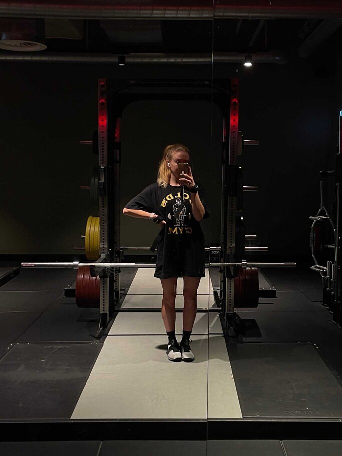Social Media Managerin Sandra steht vor einem Spiegel im Gym | © myself