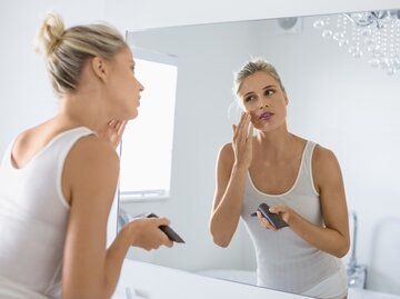 Frau trägt vor dem Spiegel eine Gesichtscreme auf | © Getty Images/Letizia Le Fur