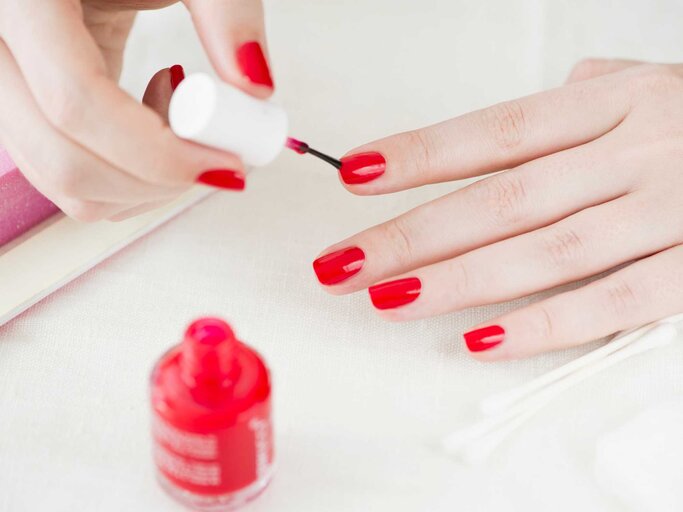 Frau lackiert sich die Fingernägel rot | © Getty Images/Tetra Images