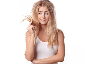 Blonde Frau fasst frustriert eine Haarsträhne an | © Getty Images/LarsZahnerPhotography
