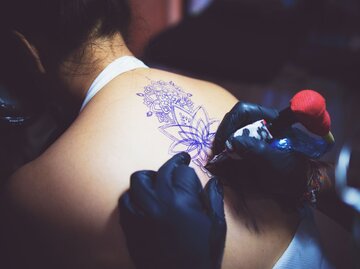 Frau bekommt Tattoo am Rücken gestochen | © Getty Images/GCShutter