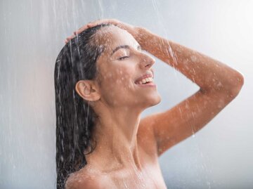 Junge Frau duscht und lächelt dabei | © Getty Images/YakobchukOlena