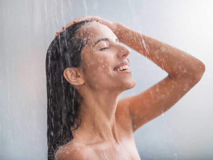 Junge Frau duscht und lächelt dabei | © Getty Images/YakobchukOlena