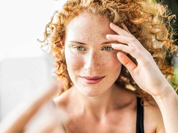 Frau mit Sommersprossen schießt ein Selfie | © Getty Images/Westend61