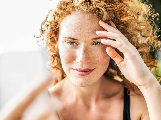 Frau mit Sommersprossen schießt ein Selfie | © Getty Images/Westend61