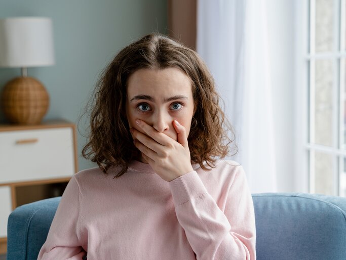 Eine junge Frau ist erschrocken und hat die Hand vor dem Mund | © GettyImages/Westend61