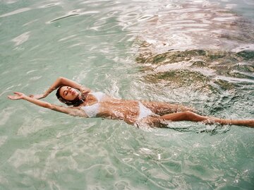 Eine junge Frau schwimmt auf dem Rücken im Meer | © GettyImages/Friend of Mars