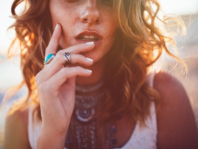 Nahaufnahme des Gesichts einer gebräunten jungen Frau mit welligen Haaren und viel Schmuck | © GettyImages/wundervisuals